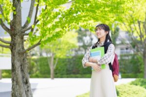 専門学校のキャンパスで奨学金を活用しながら笑顔で学ぶ母子家庭の学生のイメージ