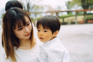 母子家庭の母親が幼い子どもを優しく抱きしめる様子。働けない時期を支える支援制度のイメージ。