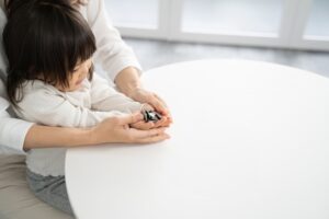 母子家庭の母親が小さな子どもと一緒に将来のためのお金を見つめている様子。遺産相続や生活の不安に寄り添うイメージ。