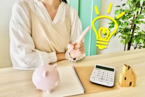 母子家庭のお母さんが家計簿と電卓を使って生活費をシミュレーションし、収入で暮らしていけるか考えている様子